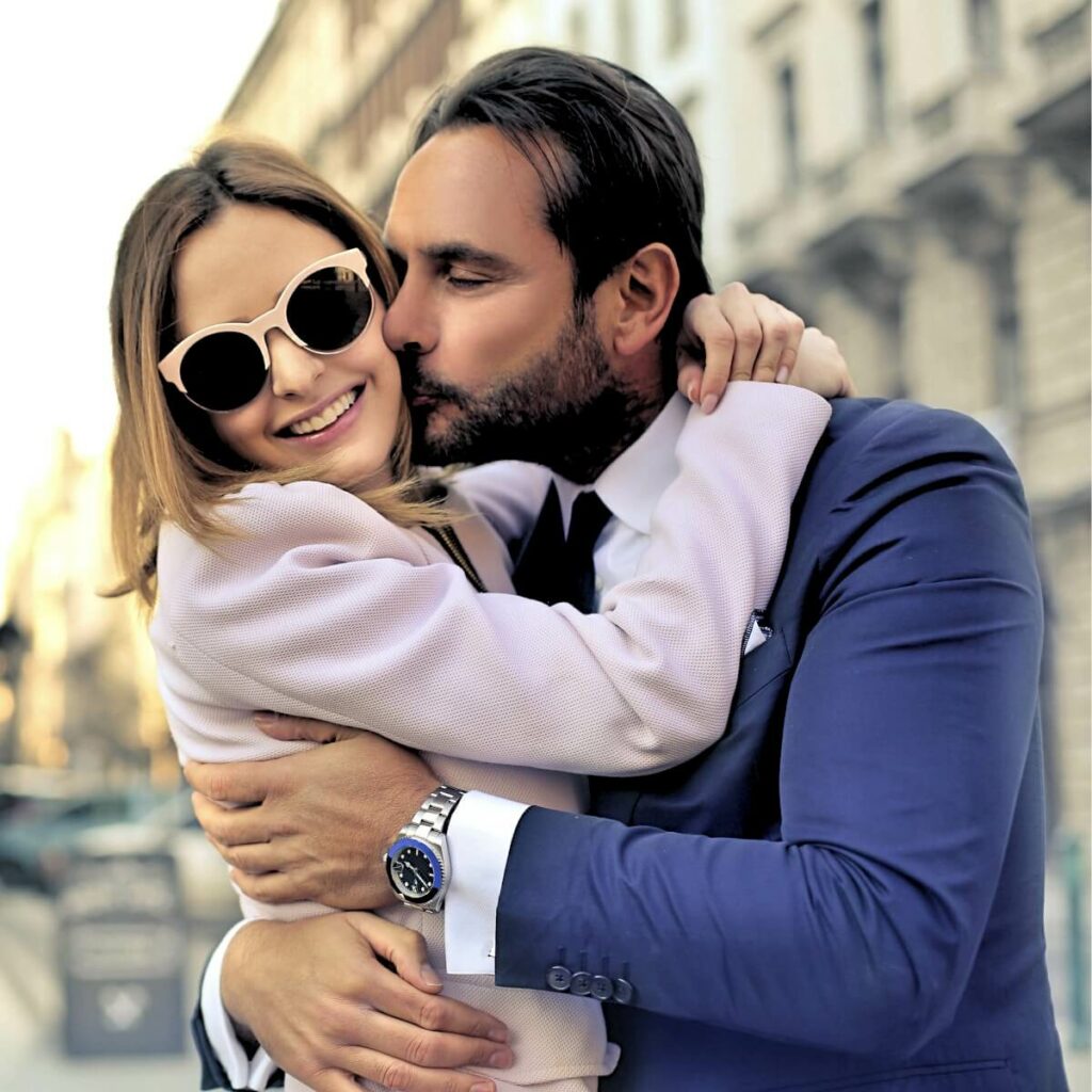 A woman hugging a man on the street, making him miss her.